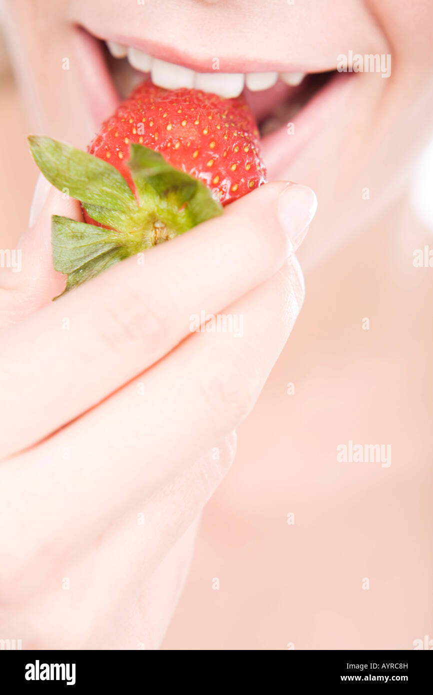 Young woman biting into a strawberry Stock Photo
