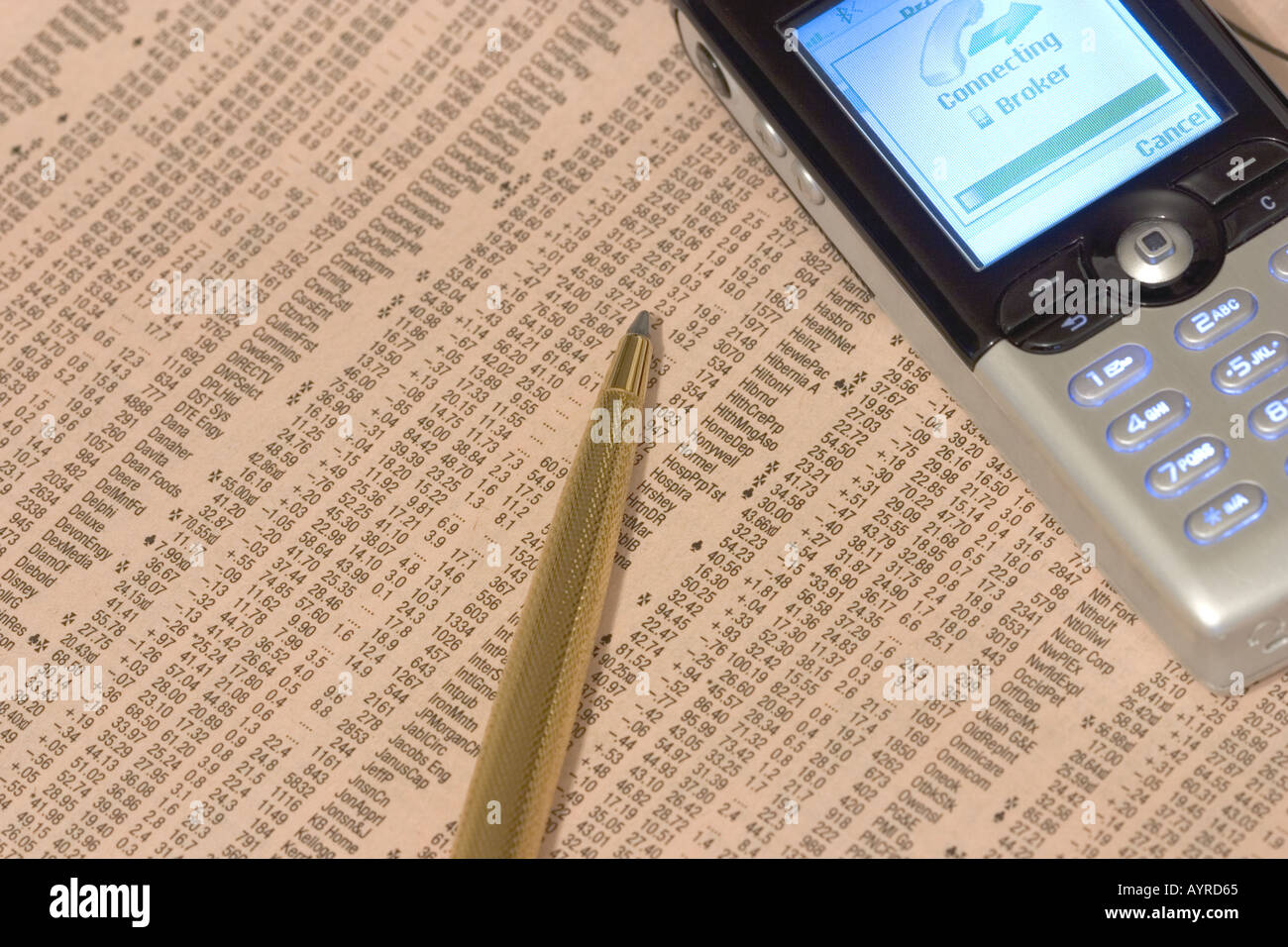 Stock price listings with gold pen and mobile telephone cell phone calling share broker Stock Photo