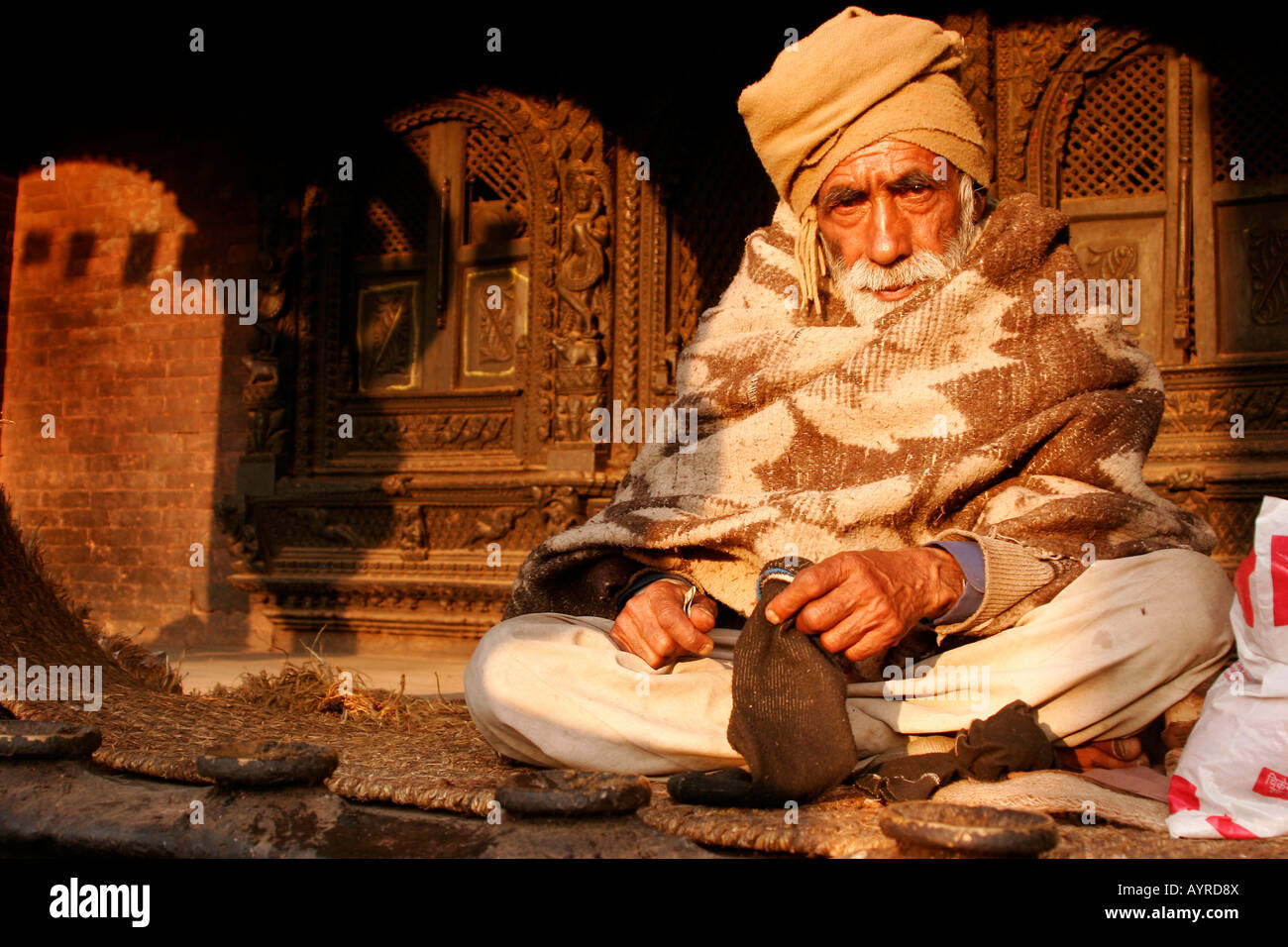 Old man sitting cross-legged in front of Dattatreya Temple in Bhaktapur, Nepal, Asia Stock Photo