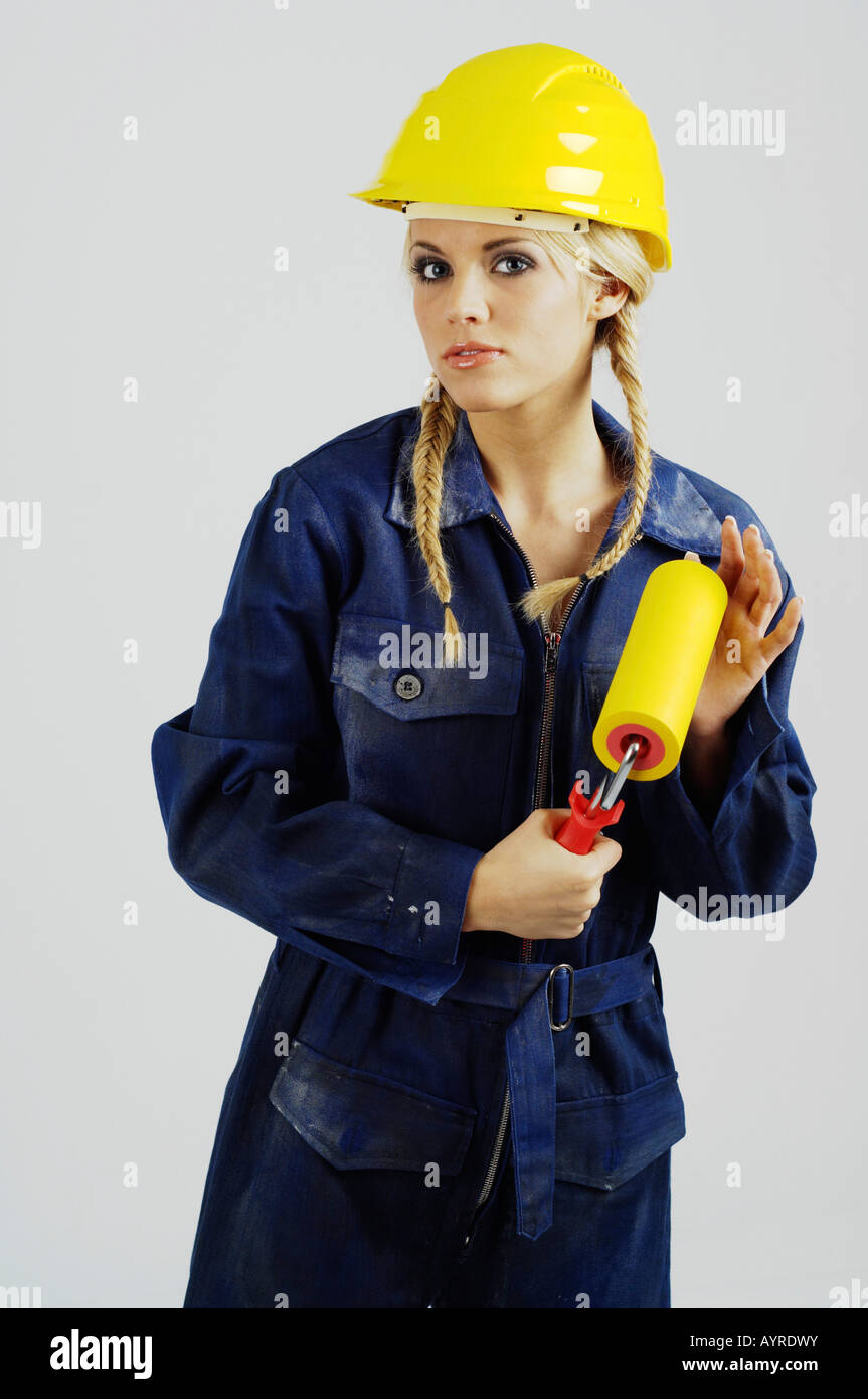 Young female construction worker wearing hardhat holding a paint roller Stock Photo