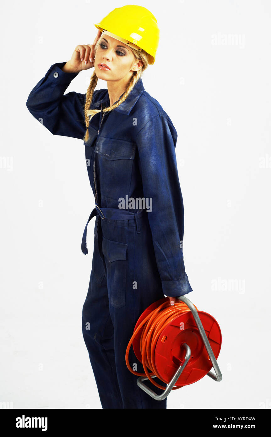Young female construction worker wearing hardhat holding a cable reel Stock Photo
