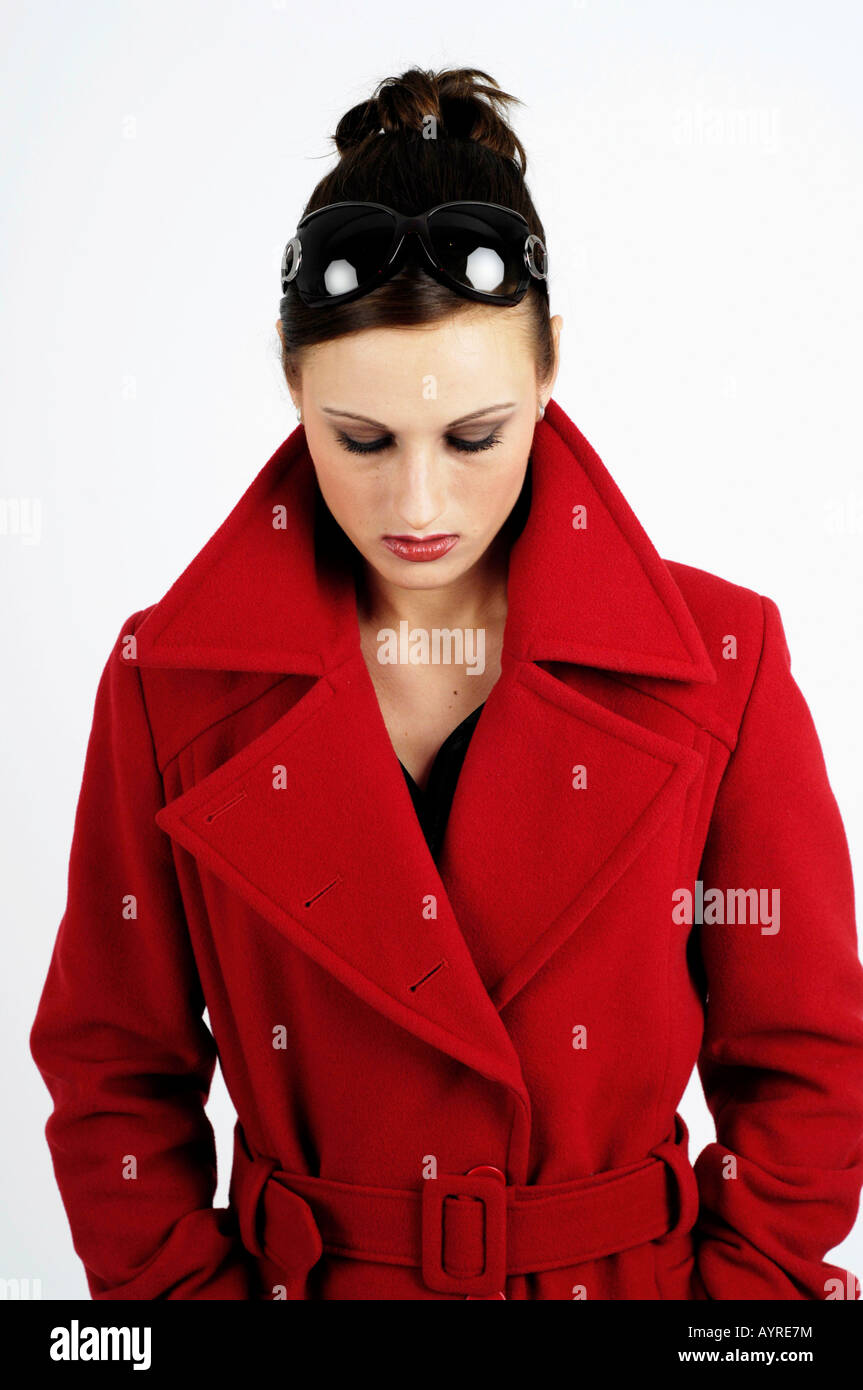 Young woman wearing red coat and sunglasses looking serious Stock Photo