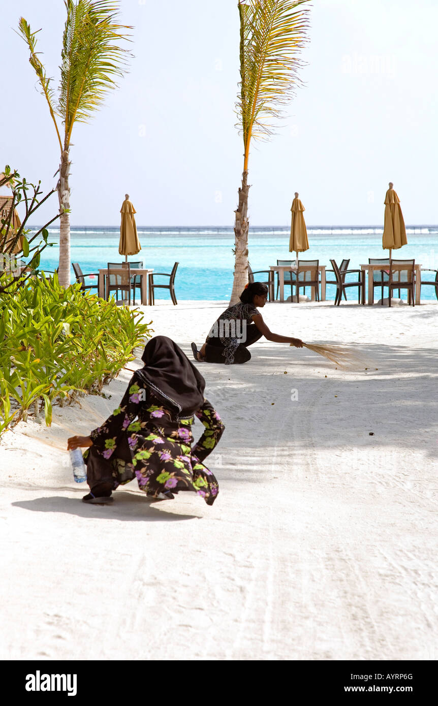 Every morning local ladies can be seen cleaning and sweeping the beaches at Anantara Resort in the Maldives Stock Photo