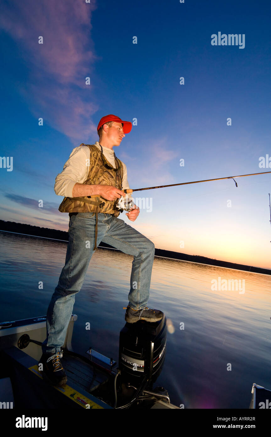 A FISHERMAN FISHES FROM A BOAT FOR WALLEYES AT DUSK ON BIG STONE LAKE