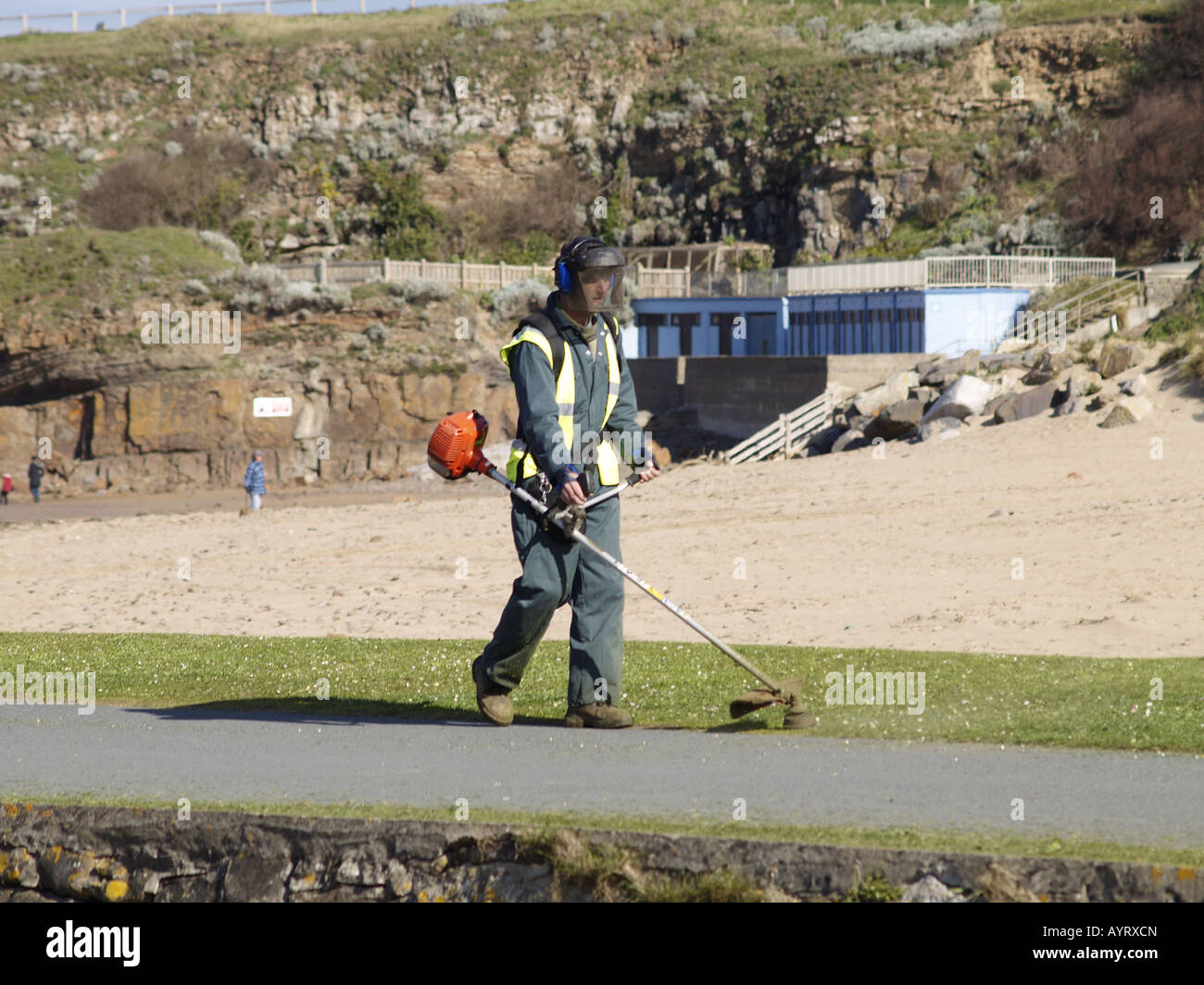 Council workman strimming grass along the side of the canal. Bude, Cornwall, UK Stock Photo