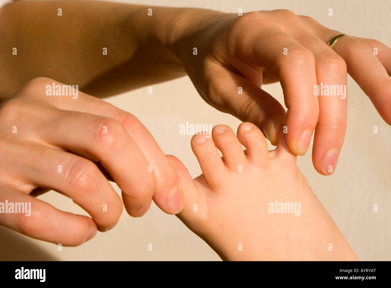 Woman's hands tugging at child's toes Stock Photo
