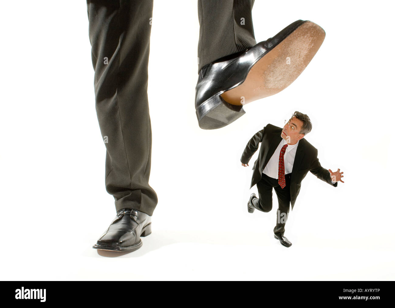 Giant foot stepping on a kneeling businessman running away Stock Photo