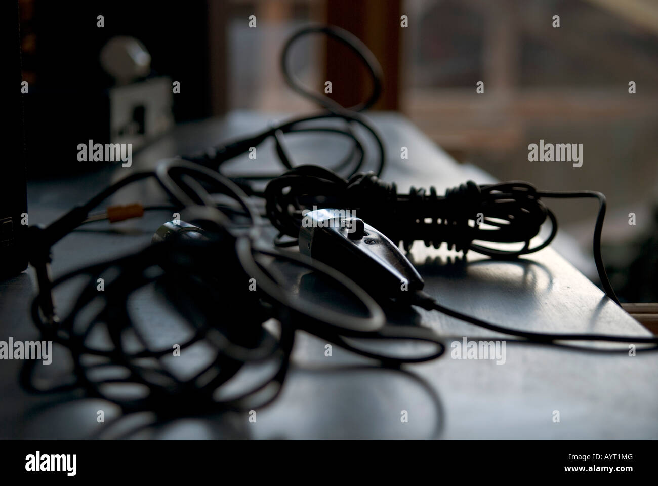 a complex web of wires and a microphone lie in low light on a table in