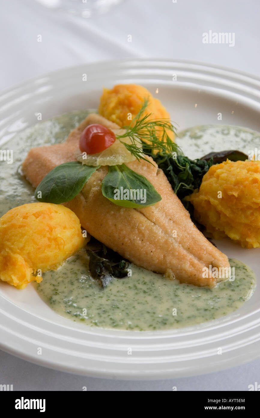 Fresh fish filet served with scalloped potatoes, spinach and herb cream sauce Stock Photo