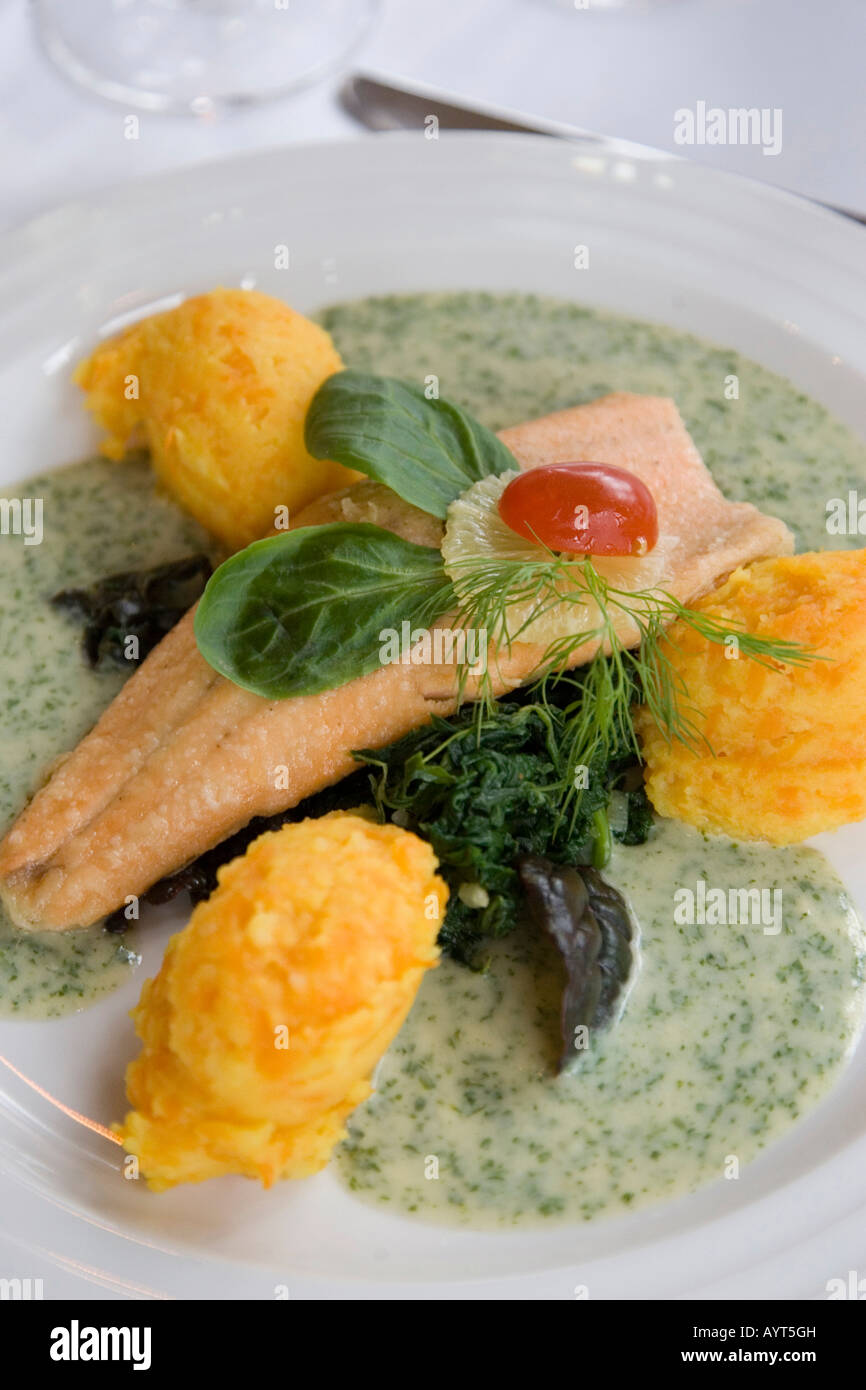 Fresh fish filet served with scalloped potatoes, spinach and herb cream sauce Stock Photo