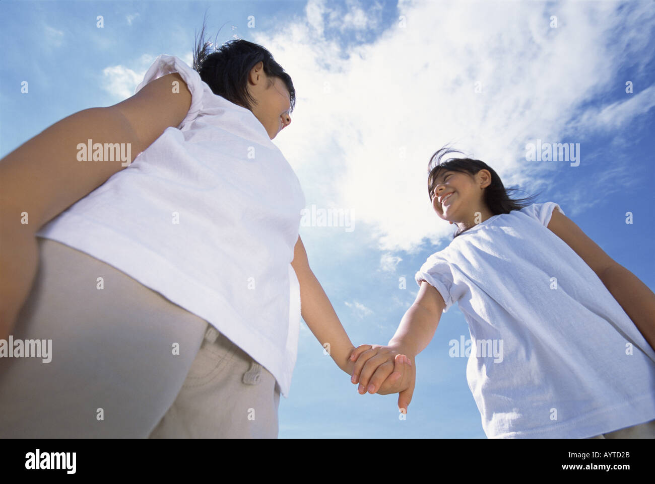 Two girls holding hands smiling at each other Stock Photo