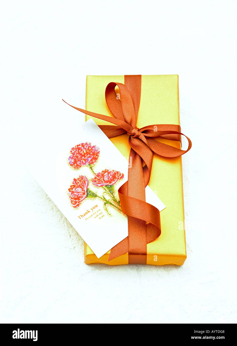 Thank you gift wrapped in gold wrapping paper with a brown bow Stock