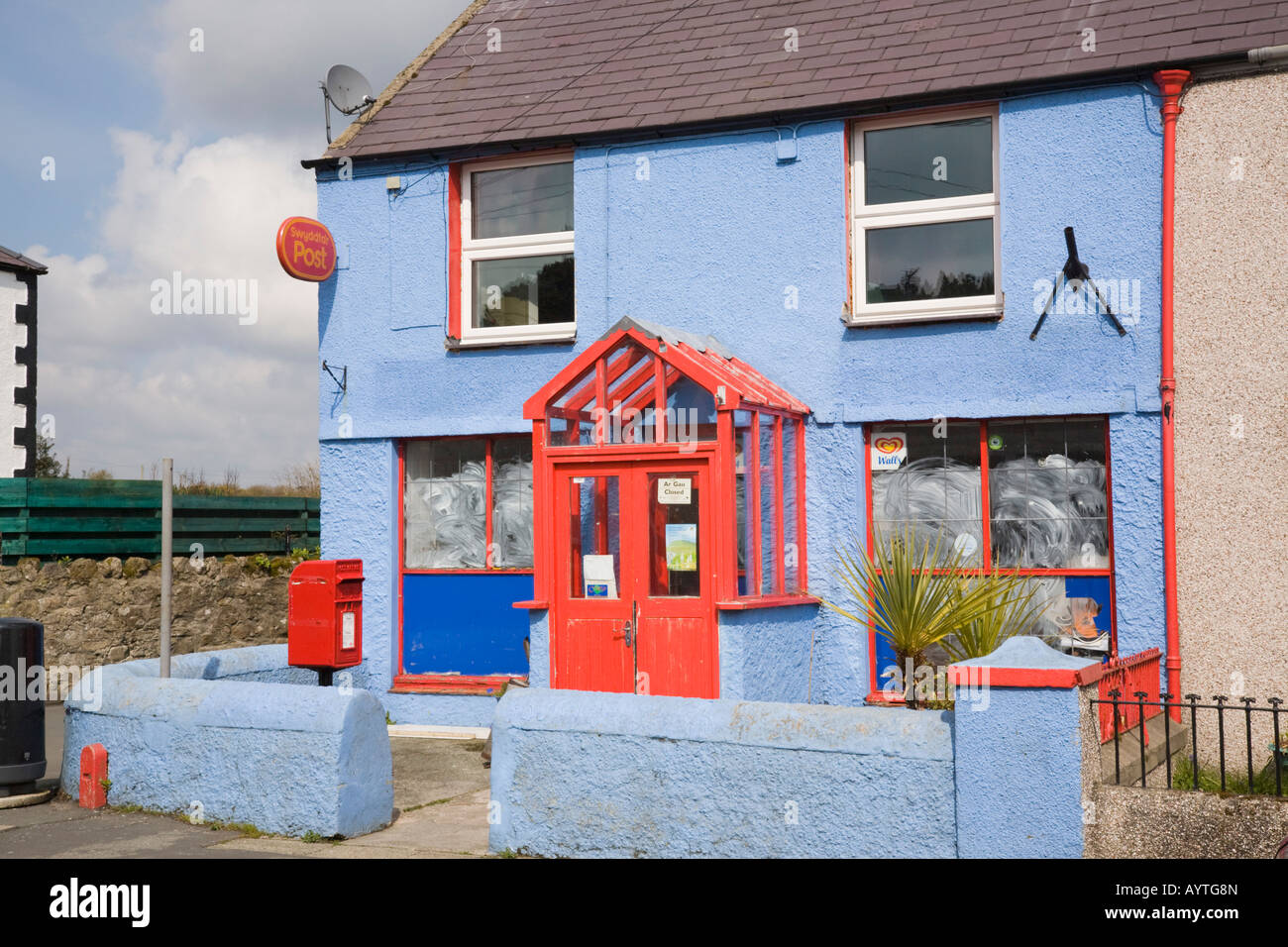 Closed village post office in colourful red and blue cottage building with post box outside North Wales UK Stock Photo