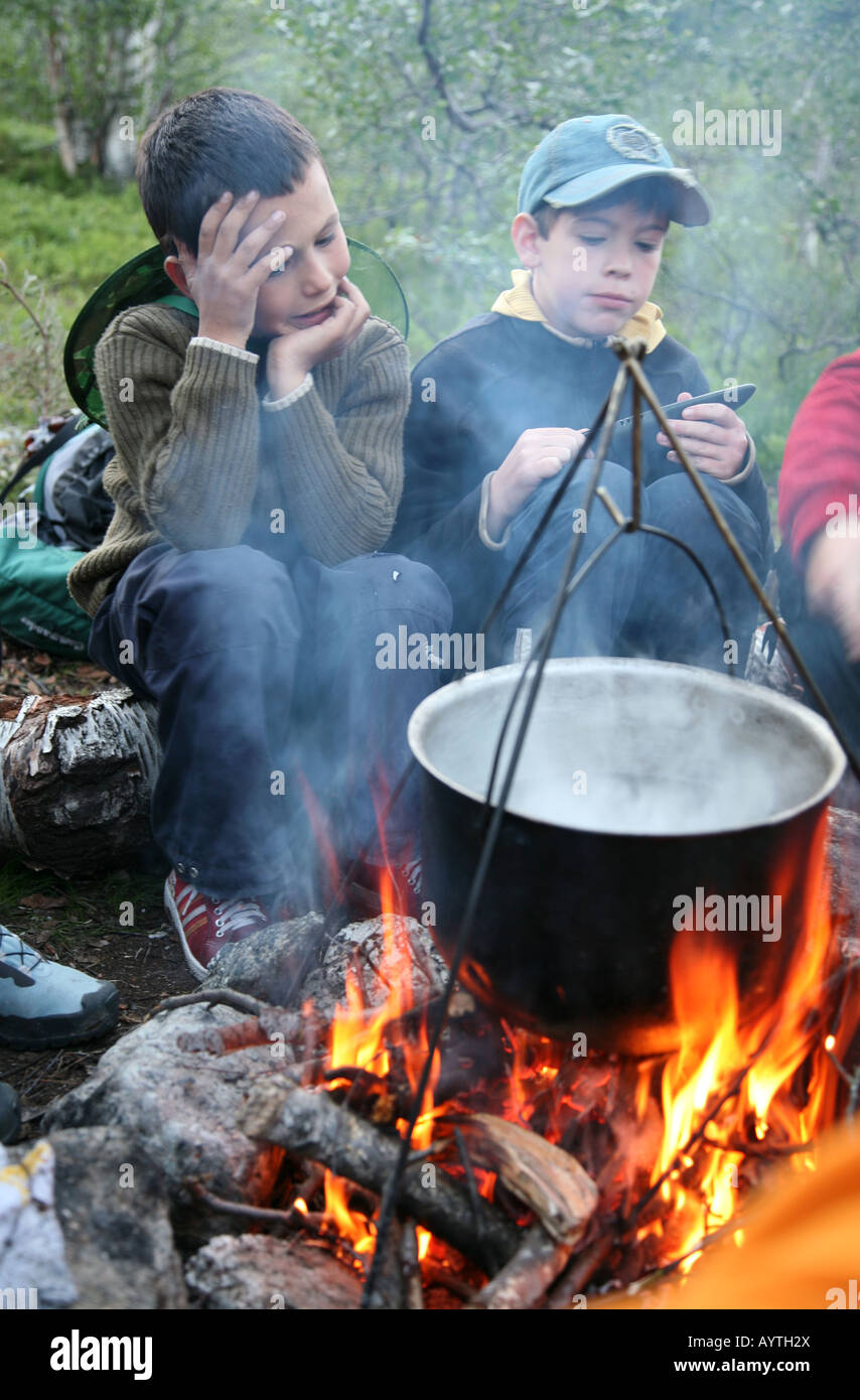Two boys cooking on the fire during a trekking in the Khibiny mountains of the Kola Peninsula, Russia Stock Photo