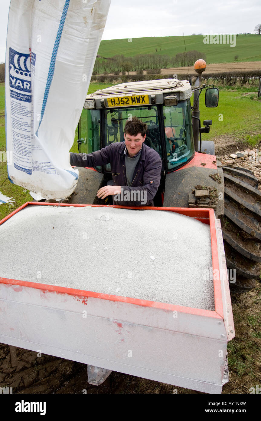 Farmer loading fertiliser spreader with chemical fertiliser for use on