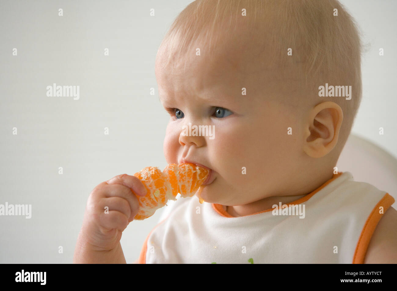 Toddler eating a mandarin by himself Stock Photo