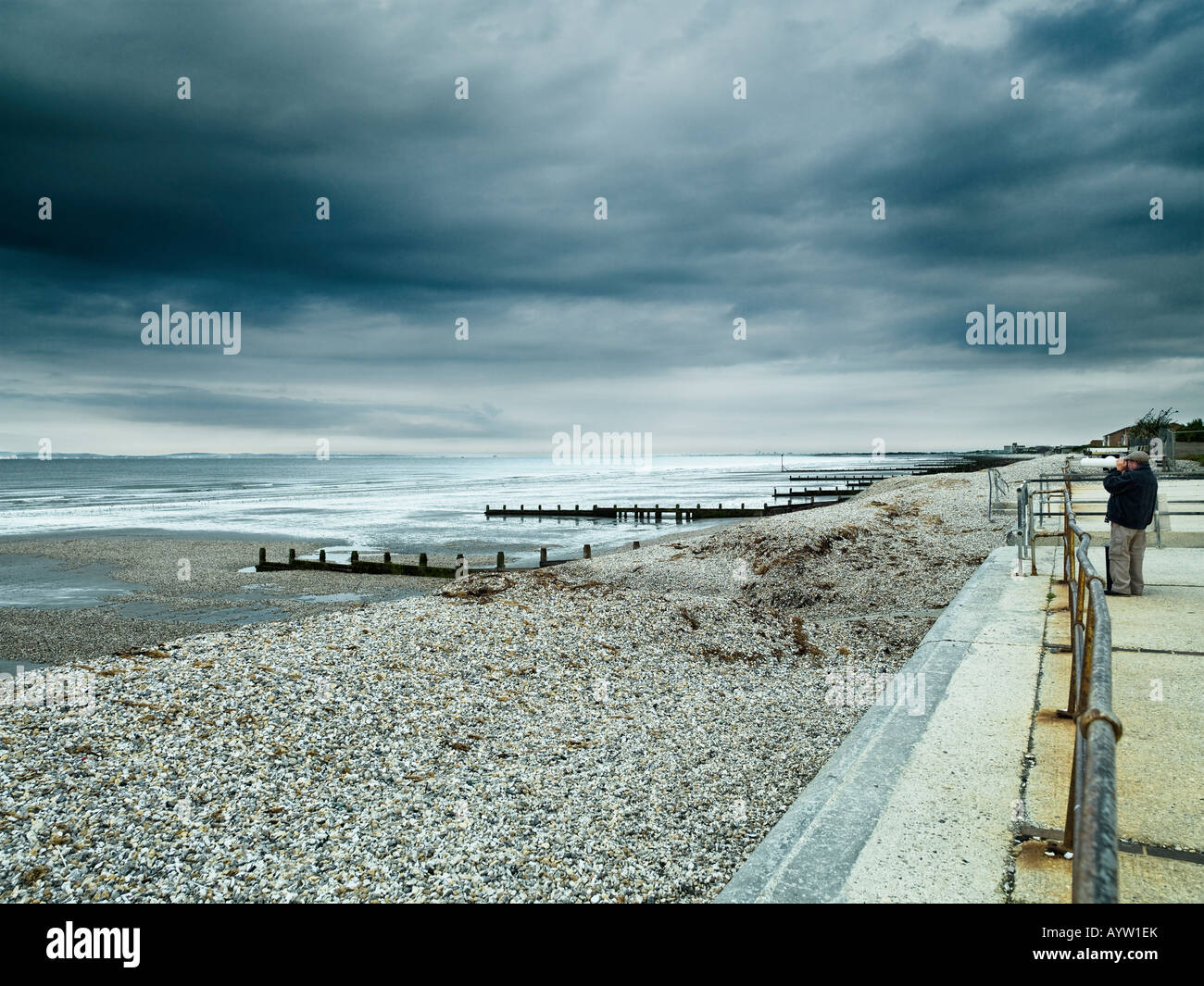 man looking through a telescope, out towards the sea at the seaside ...