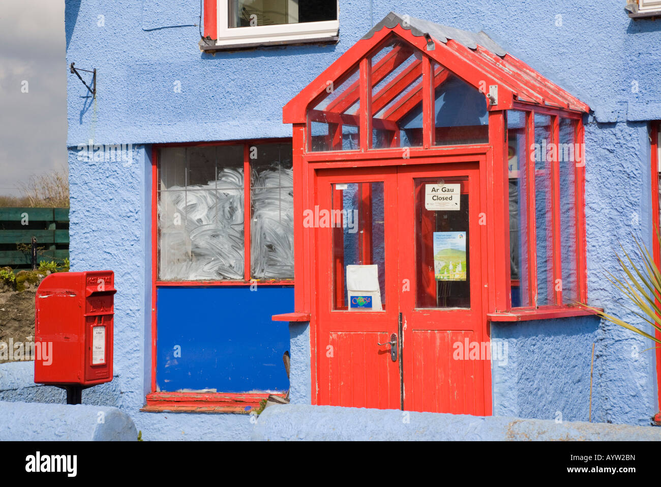 Closed village post office in colourful red and blue building with post box outside North Wales UK Stock Photo
