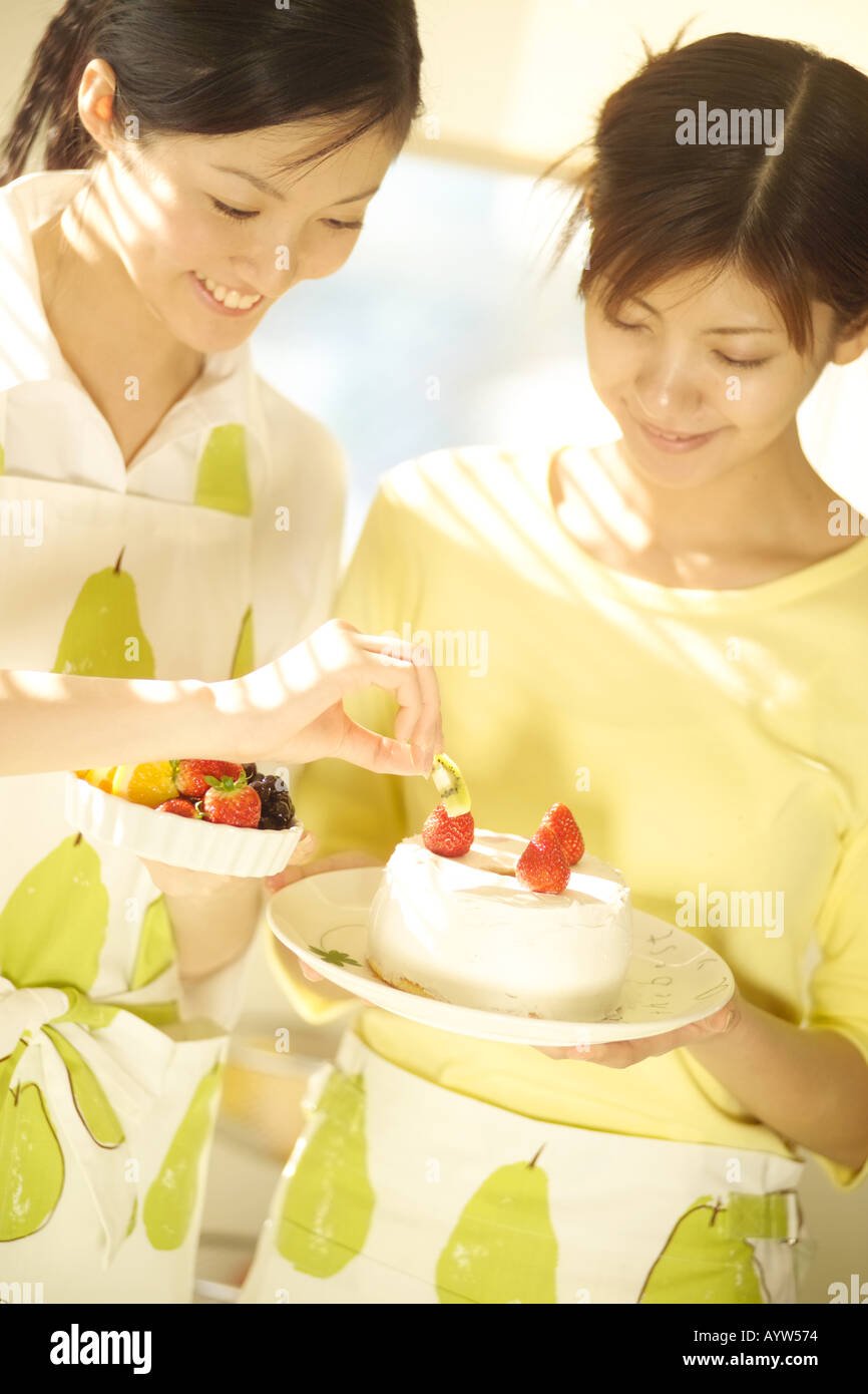 Two women decorating a cake Stock Photo