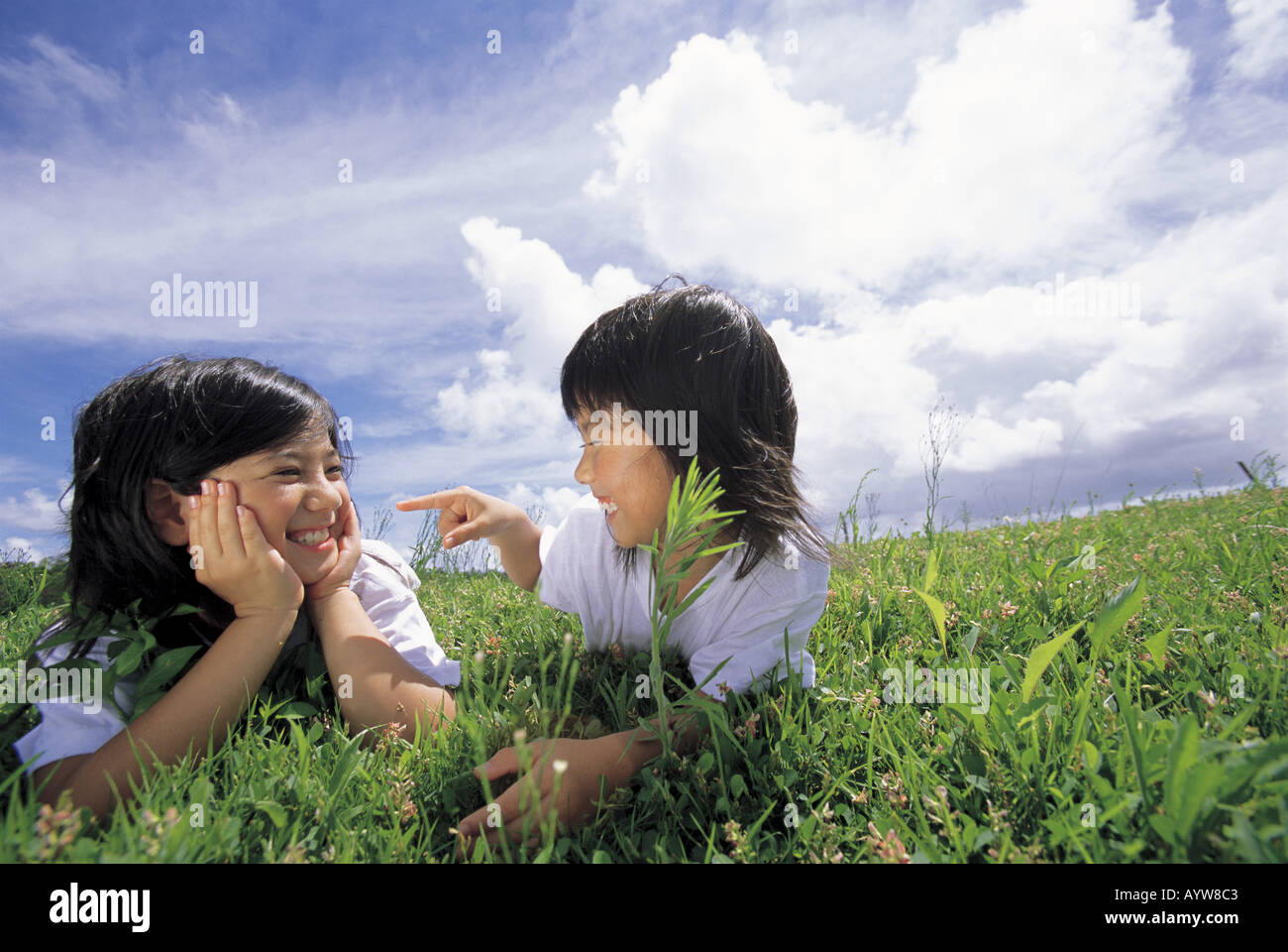 Two girls lying down in the meadow Stock Photo