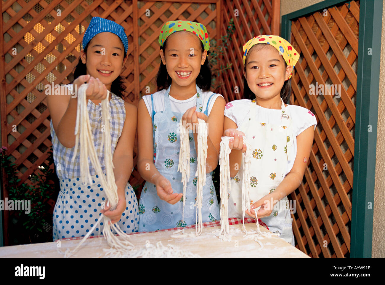 Three girls making noodle pasta Stock Photo