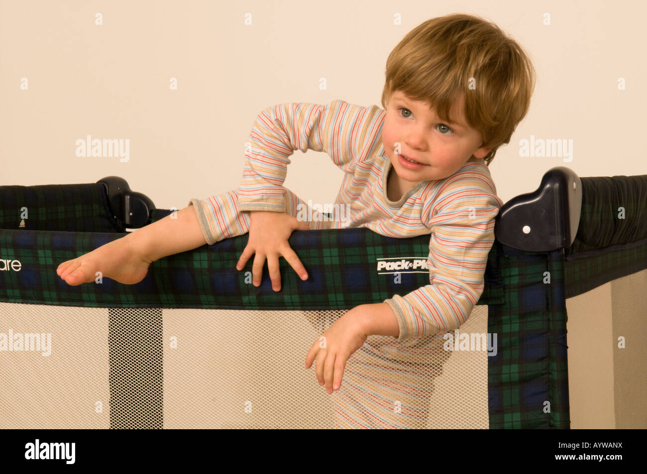 two year old boy climbing out of cot, travel cot, bed, pen Stock Photo