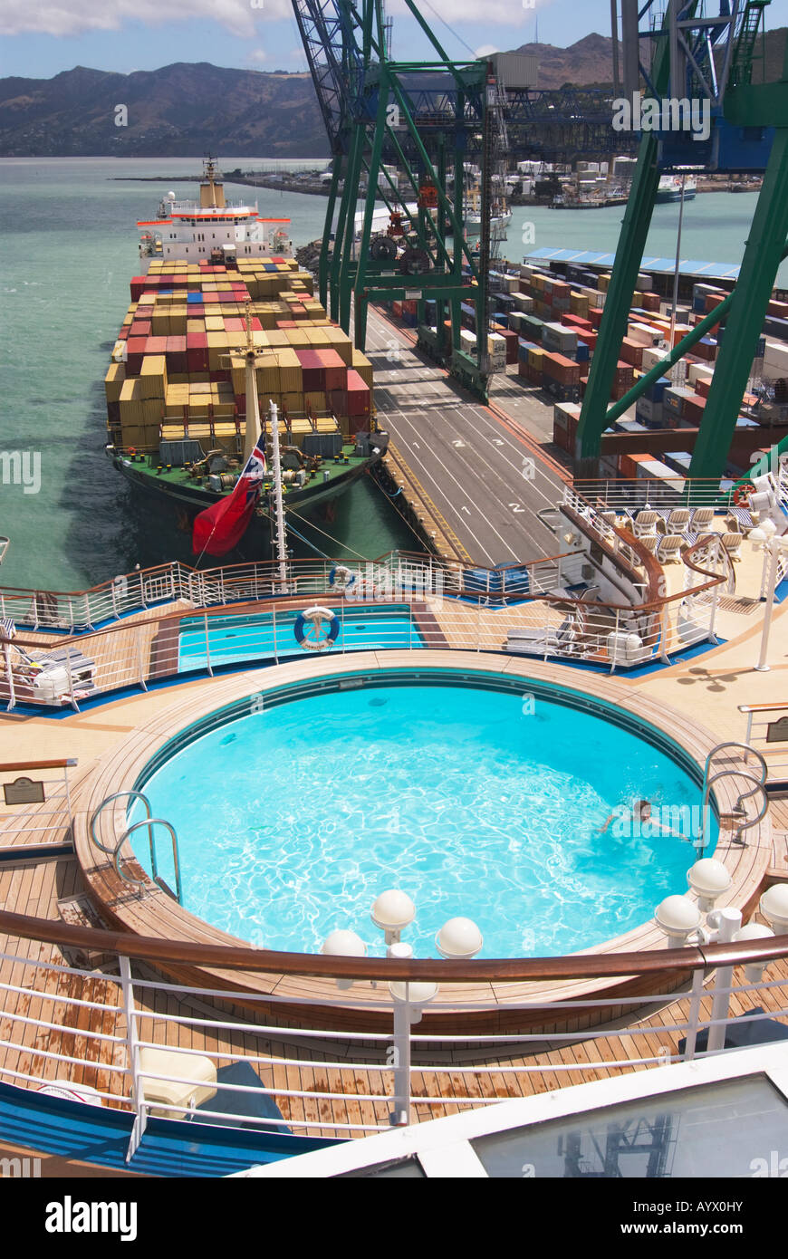 Aft decks of a cruise ship with swimming pool and a container ship