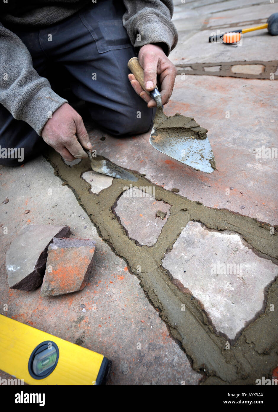 A BUILDER POINTING IN A PATIO LAID WITH NATURAL STONE SLABS UK Stock