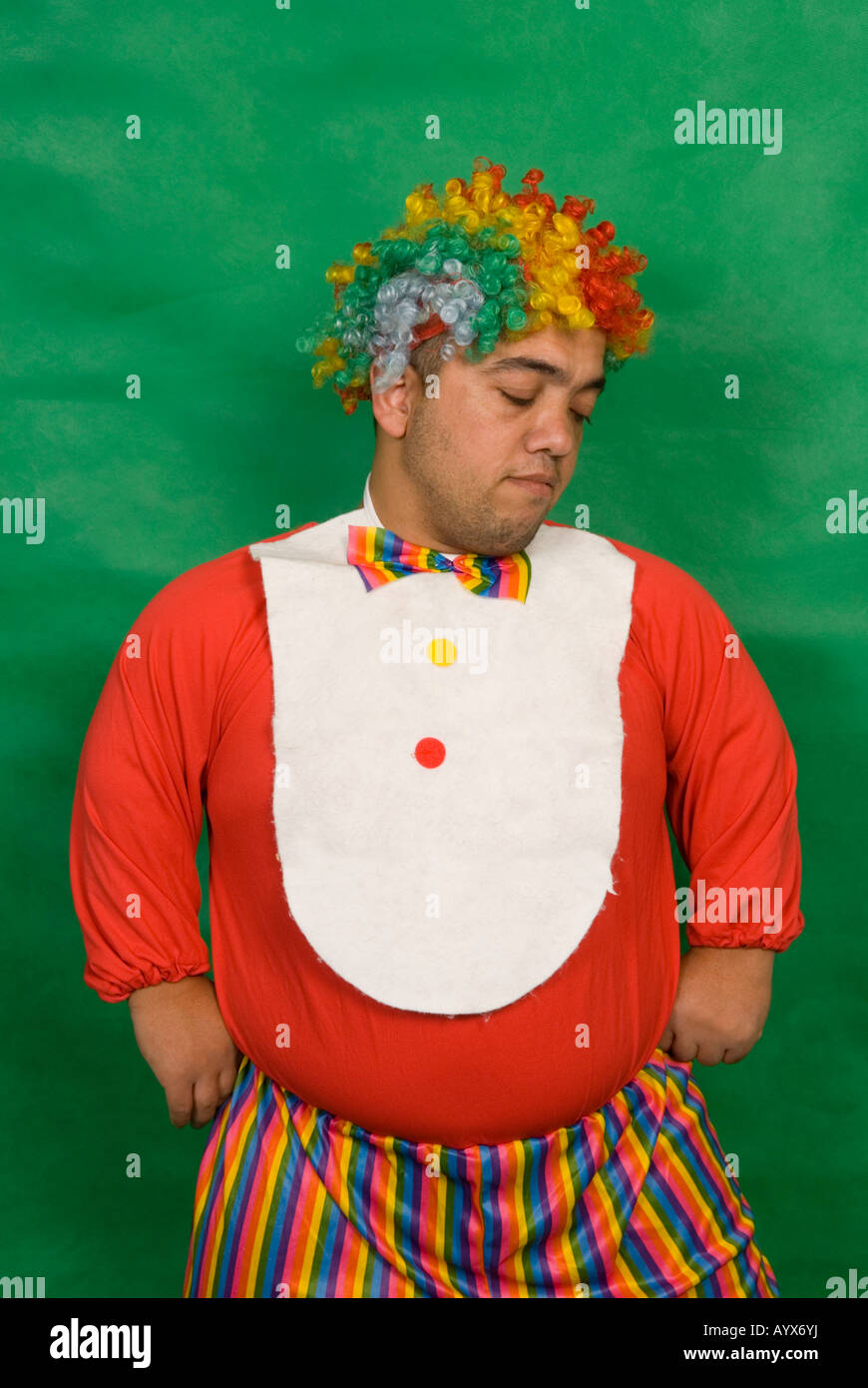 Portrait of a sad midget clown against a green background Stock Photo
