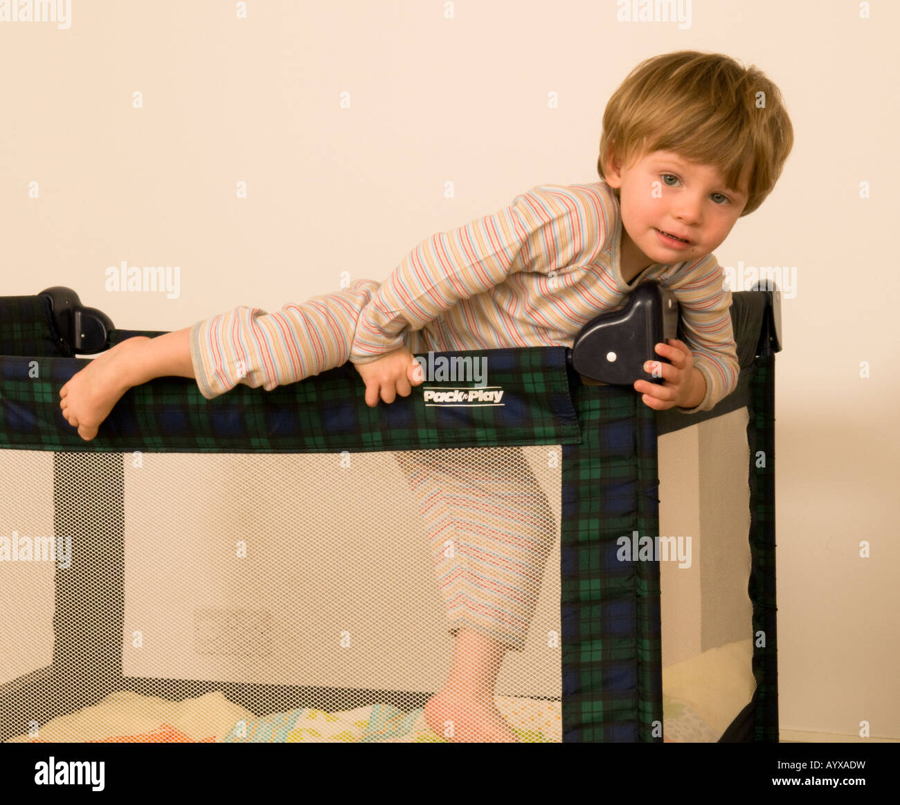 two year old boy climbing out of cot, travel cot, bed, pen Stock Photo