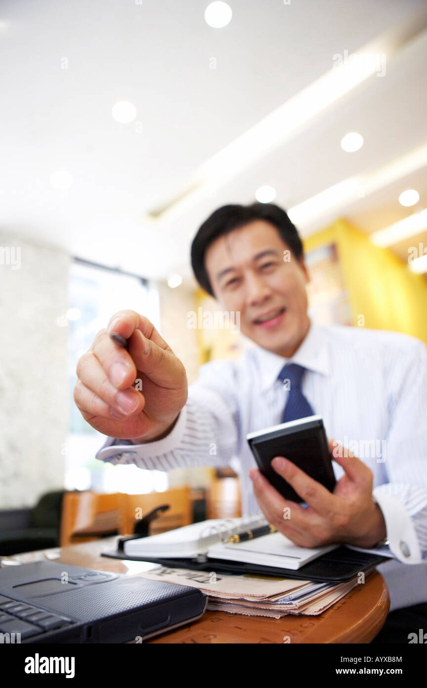 a man pointing out the front with holding PDA on his hand Stock Photo
