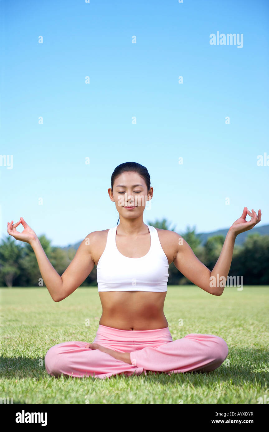 a woman sittin on grass field with motioning yoga Stock Photo - Alamy