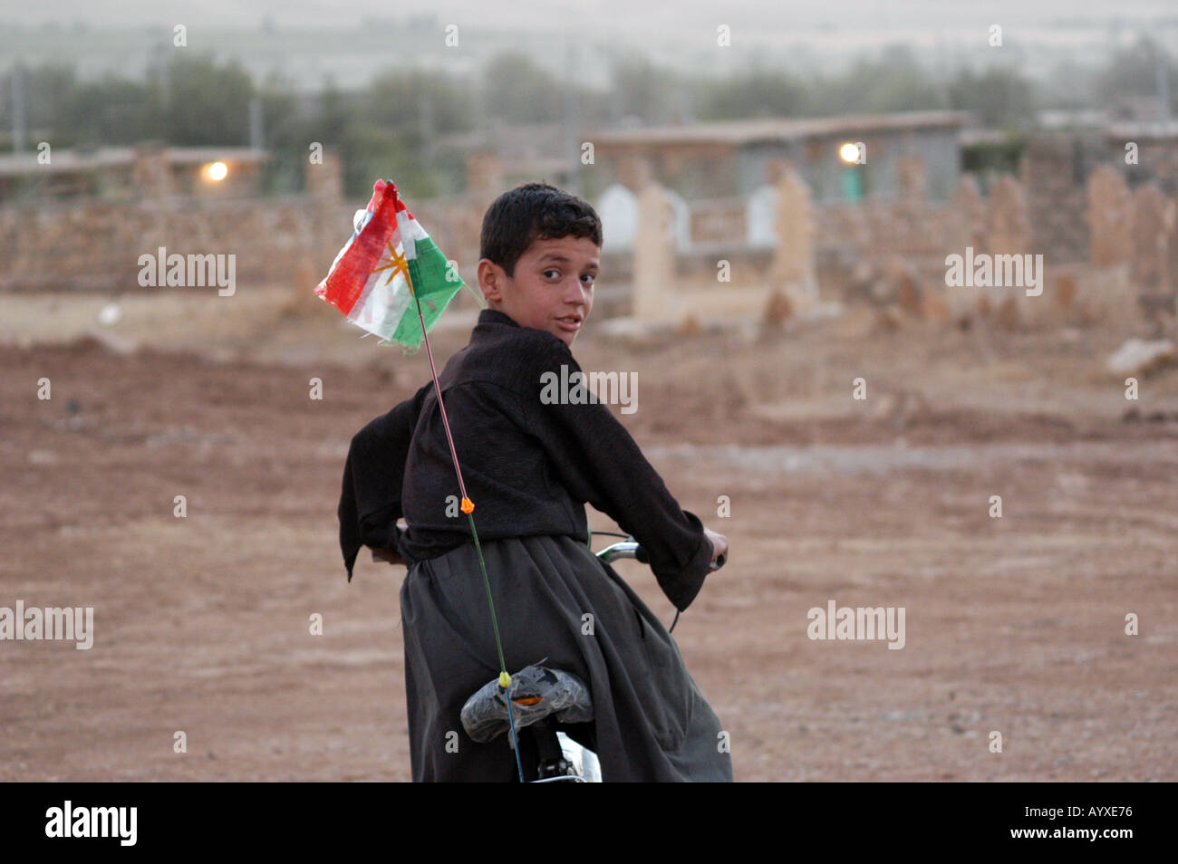 Portrait of Kurdish boy on bicycle with Kurdish rebel flag Kurdistan Northern Iraq Stock Photo