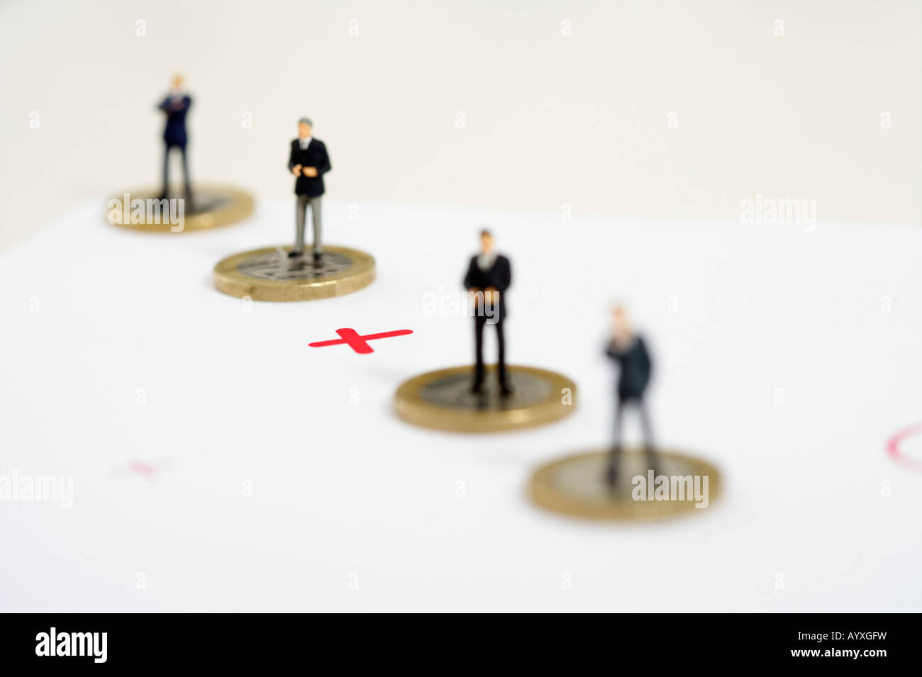 Plus sign between businessmen figurines standing on one Euro coins Stock Photo