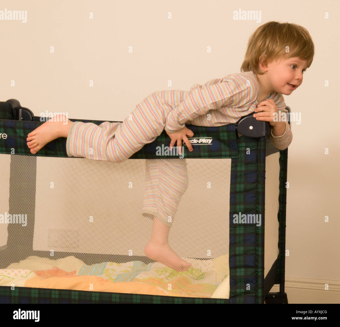 two year old boy climbing out of cot, escaping travel cot, bed, pen Stock Photo Alamy