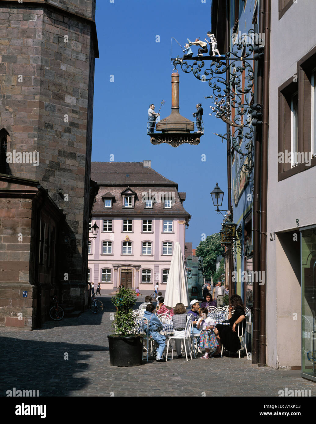 Menschen sitzen im Strassencafe, Gasthaus, Sudhaus, Wirtshausschild, Ausleger, Villingen-Schwenningen, Schwarzwald, Baden-Wuerttemberg Stock Photo