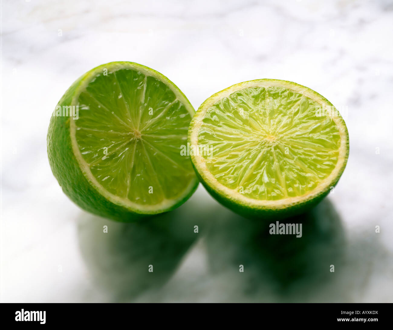 SHOT OF A WHOLE LIME CUT IN HALF ON A MARBLE SURFACE Stock Photo