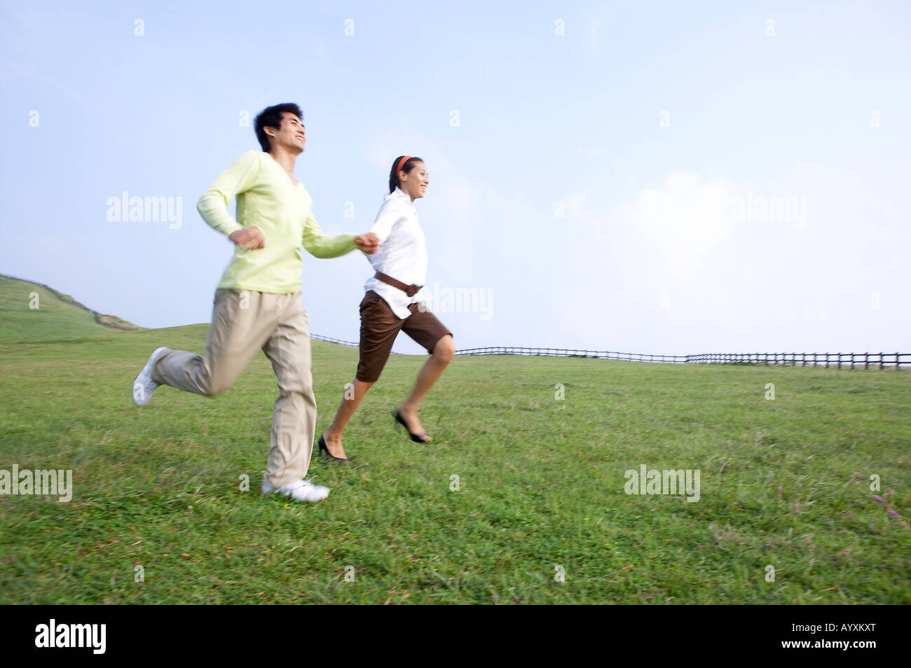 a couple grasping hands each other on the grass field Stock Photo