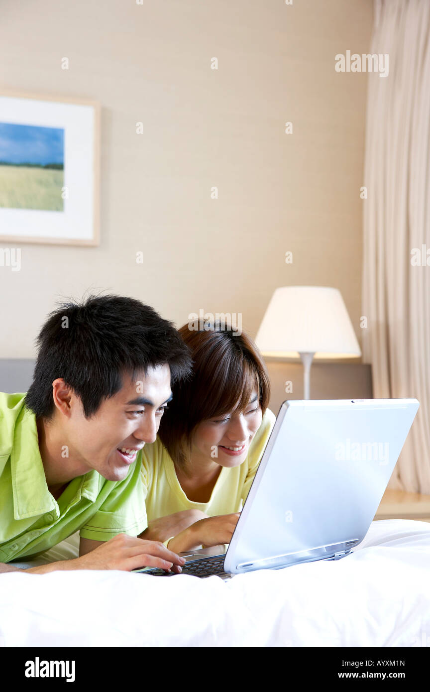 a couple who lay down on the bed and using laptop computer Stock Photo ...