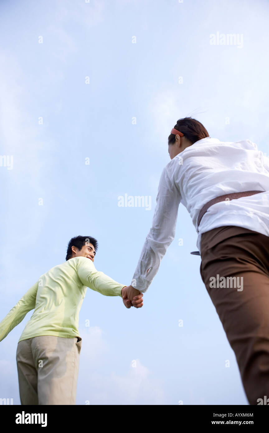 a couple grasping hands each other in the background of the sky Stock Photo