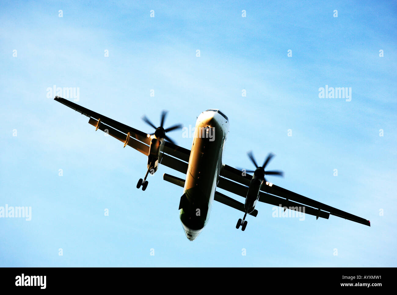 A landscape format image of a twin propeller aircraft with undercarriage down on final approach to land. Stock Photo