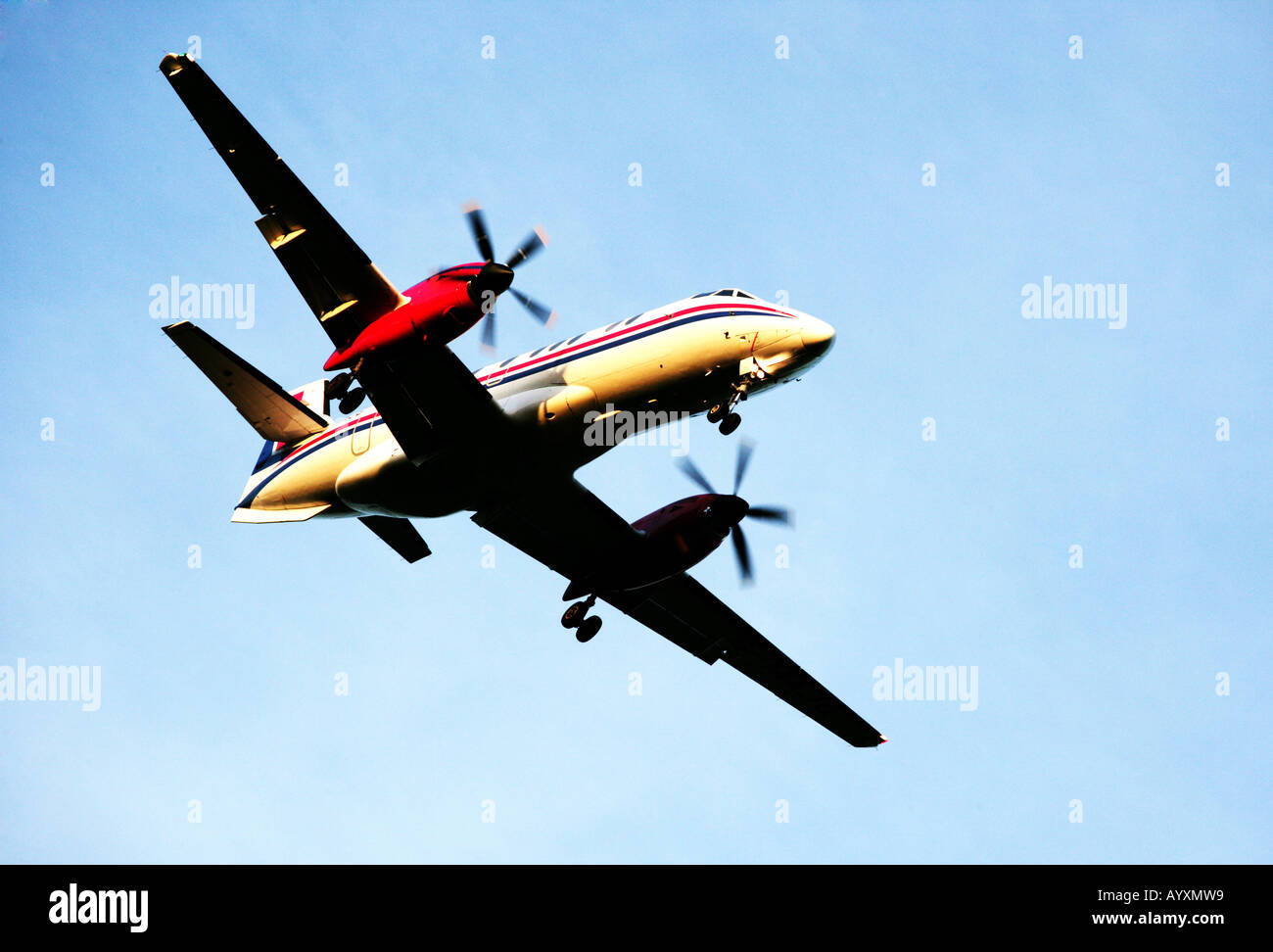A landscape format image of a twin propeller aircraft with undercarriage down on final approach to land. Stock Photo