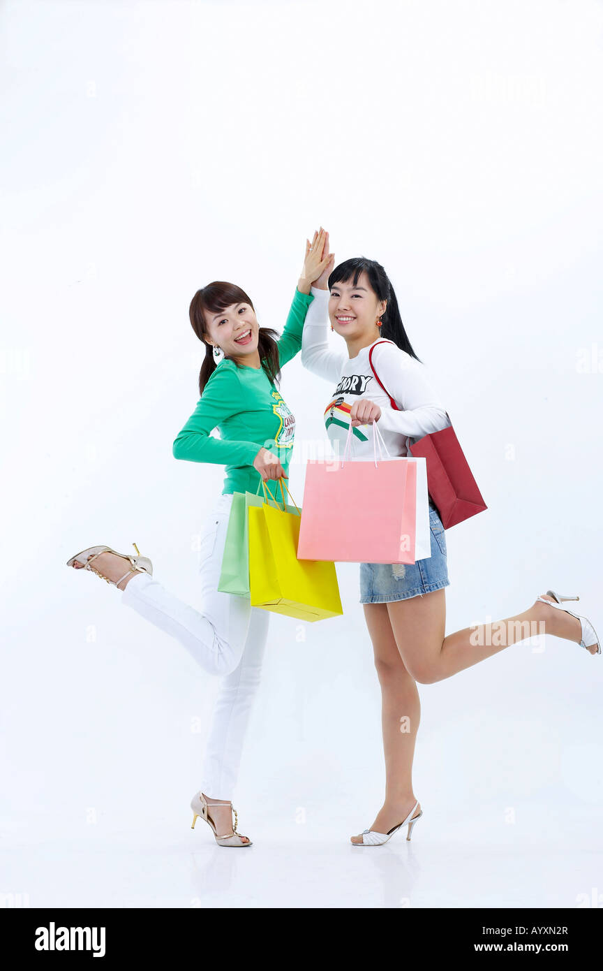women slapping high-fives with holding shopping bag fully Stock Photo