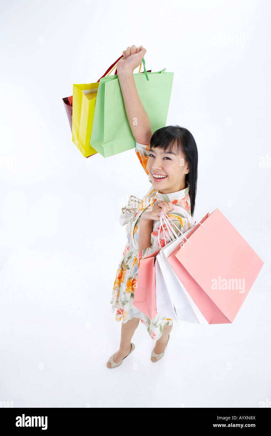 a smiling woman holding shopping bags fully to her hands Stock Photo