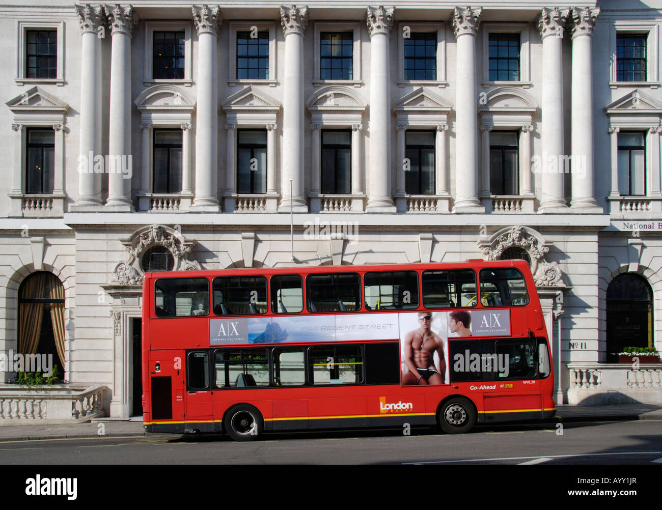 Red London bus against historical stone architecture London England Stock Photo