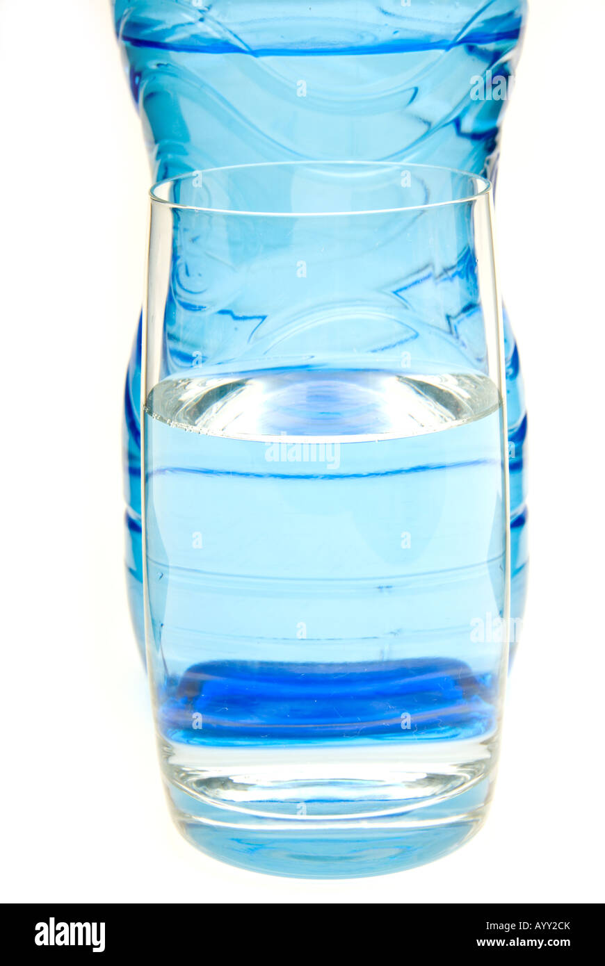 A glass of water in front of a blue bottle Stock Photo