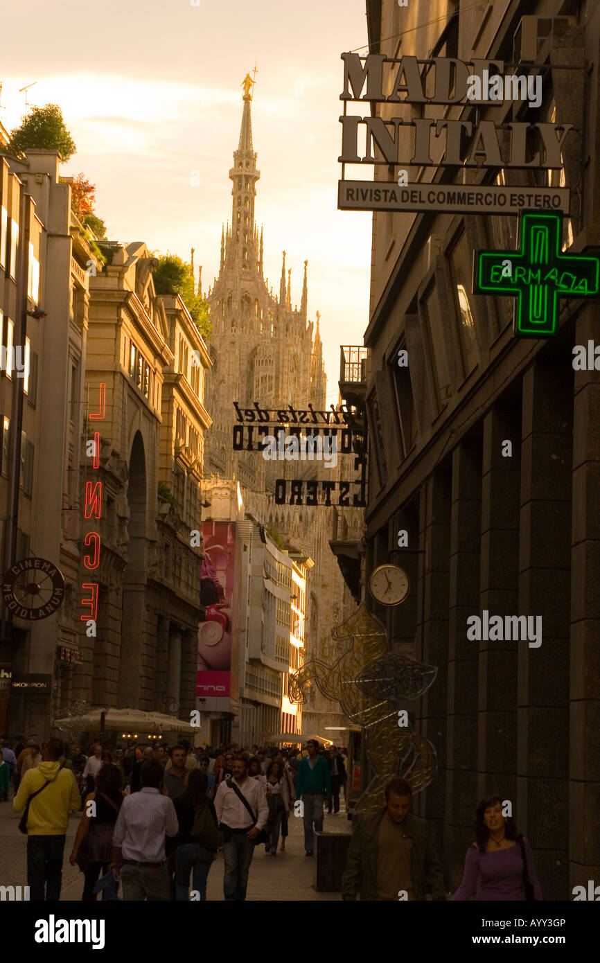 A 'Made in Italy' sign above tourists as they walk the streets in the early evening near the Duomo Cathedral in Milan Italy Stock Photo