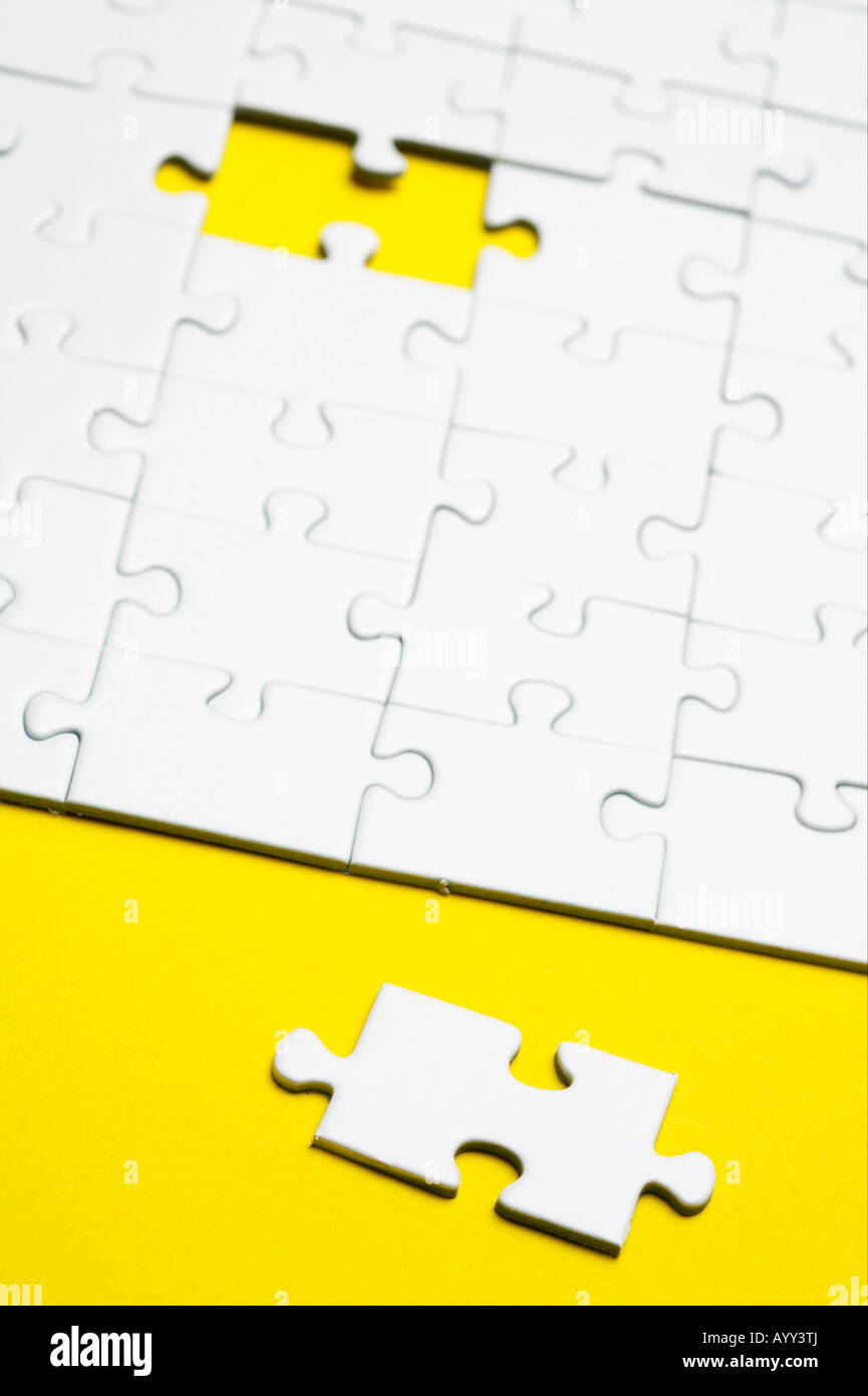Jigsaw piece lying beside a jigsaw puzzle Stock Photo