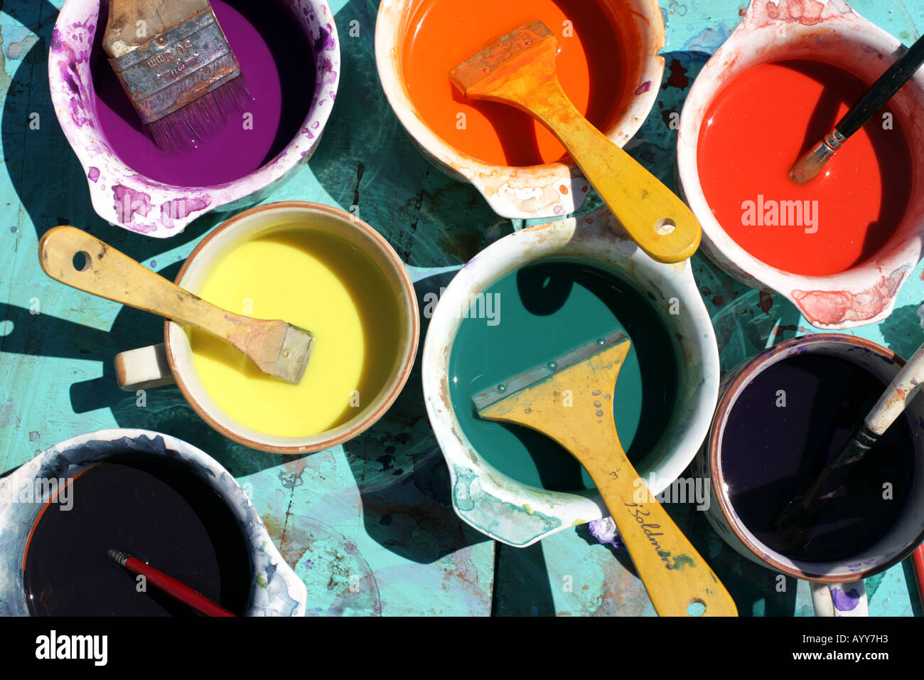 brightly coloured pots of paint with brushes Stock Photo