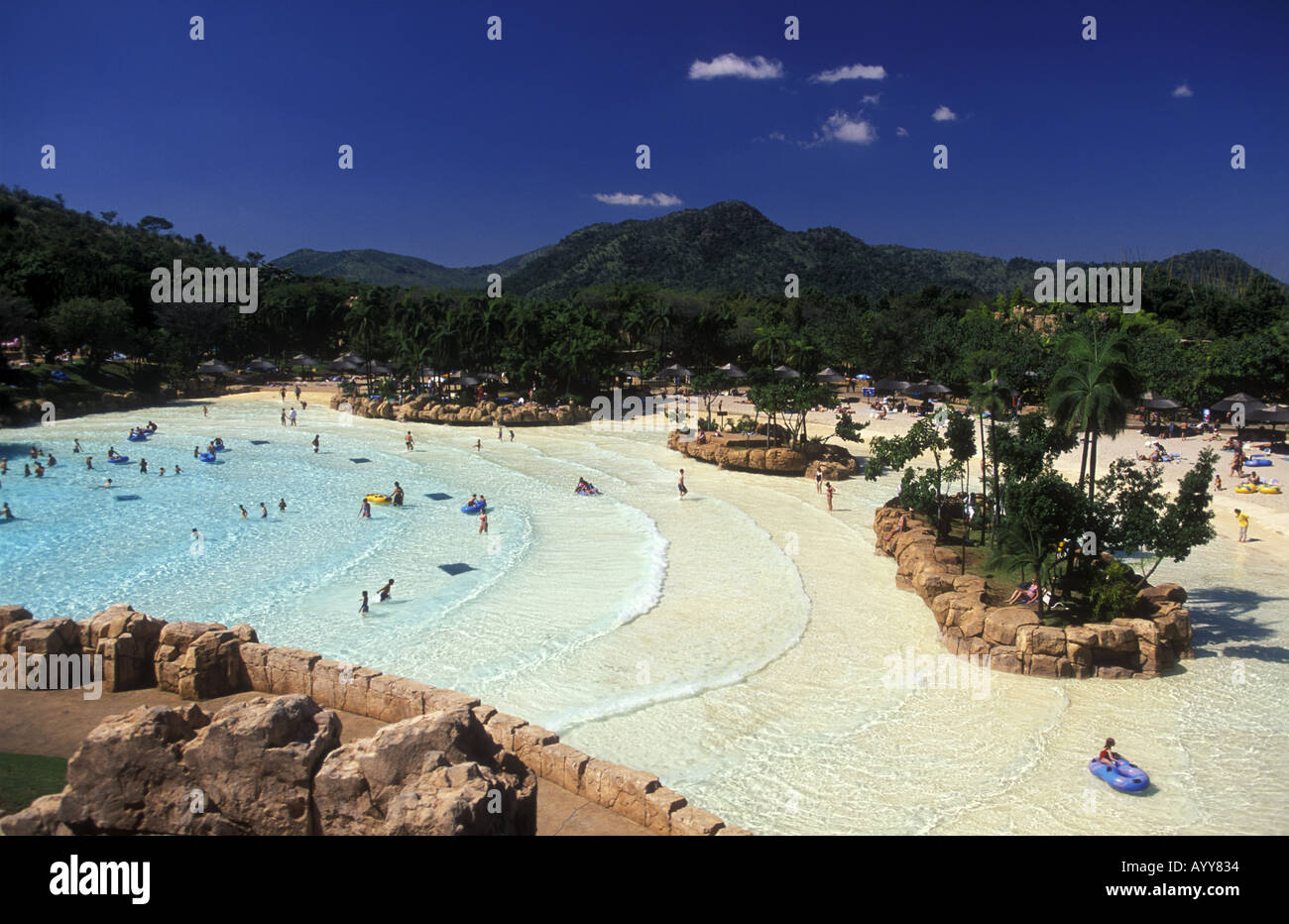 Man made beach at the Lost City complex Sun City South Africa There are many swimmers and bathers Some have rubber boats Stock Photo